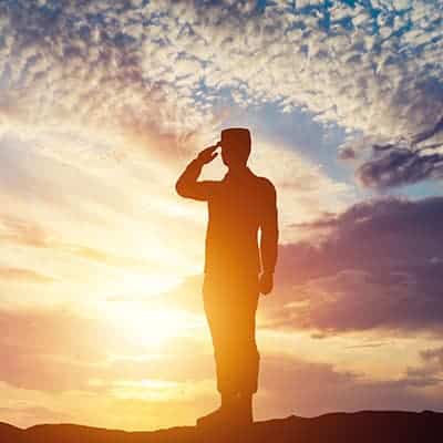 Ask us today about our Veteran Discounts! A veteran soldier saluting as the sun sets - As part of our dental savings plan, we offer discounts to veterans