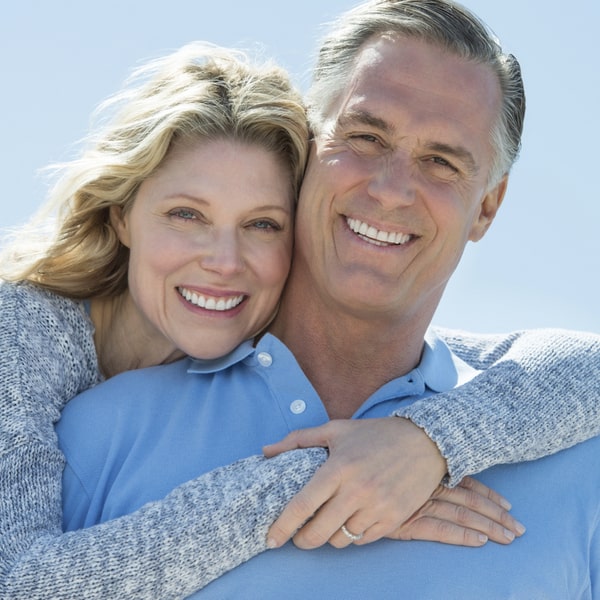 Happy middle-aged couple hugging and smiling on the beach