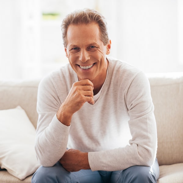 Middle-aged man happily smiling while sitting on the sofa