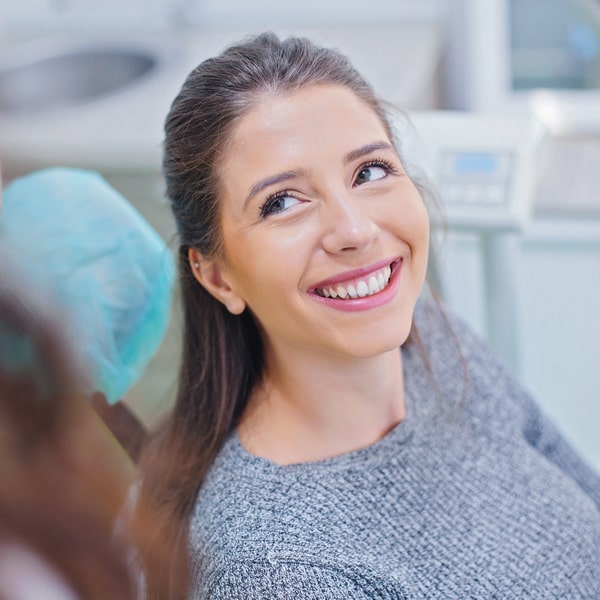 Woman in a dental chair happily smiling and looking at her dentist
