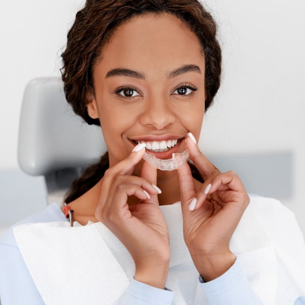 Woman is happily smiling and holding her Invisalign near her face