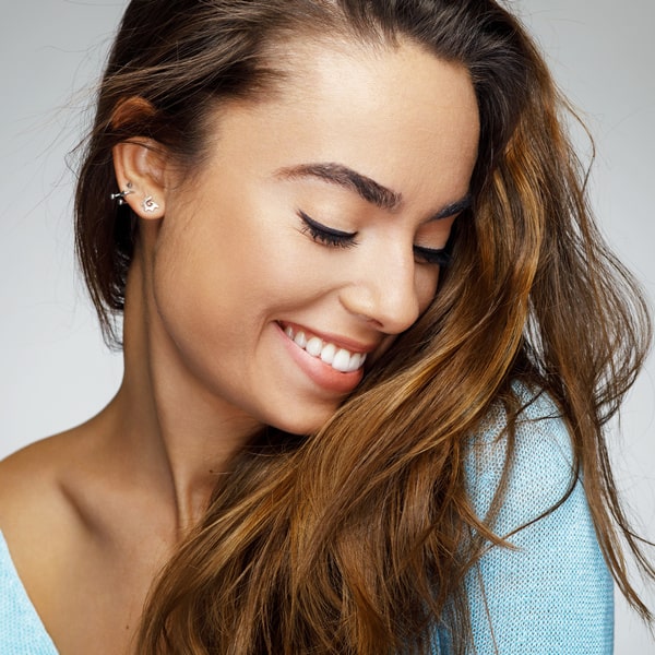 Woman with long hair and earrings smiling with relief mobile