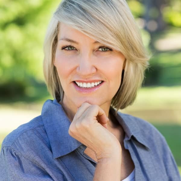 Dental care is important for overall health Middle-aged woman happily smiling in a park